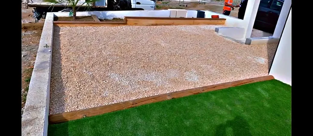 Allée en béton désactivé bordée d’une lisse bois, entre deux surfaces engazonnées