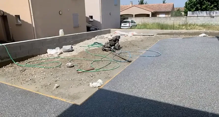Cour extérieure livrée et abords en cours de finition le long d’un mur en parpaing